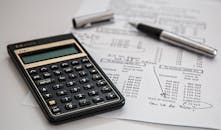 Close-up of financial documents with calculator and pen, ideal for business management themes.